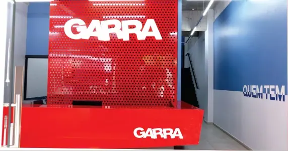 Recepção do Garra com balcão vermelho e logotipo na parede